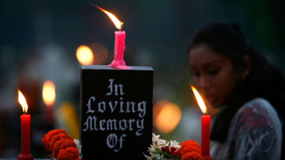 A woman stands beside the grave of her loved one in a cemetery during the observance of All Souls Day in Kolkata