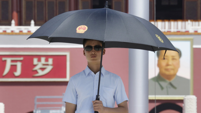 A paramilitary police officer in plain-clothes holding an umbrella keeps watch on Beijing's Tiananmen Square, August 27, 2015. Major Western leaders will not attend a military parade in China next week to mark the end of World War Two, leaving President Xi Jinping to stand with leaders and officials from Russia, Sudan, Venezuela and North Korea at his highest-profile event of 2015.