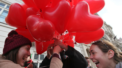 girls hold heart-shaped balloons