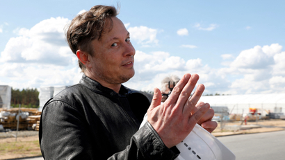 Elon Musk making a jokey face with a white safety helmet in his hands
