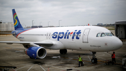 A Spirit airplane sits outside an airline gate.