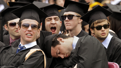 A group of college students at their graduation, with one having fallen asleep.