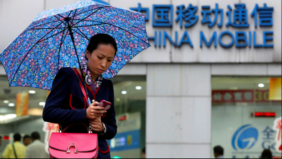 A woman uses her mobile phone in front of a China Mobile office in downtown Shanghai