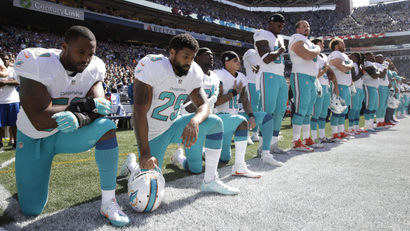 Miami Dolphins' players kneel during the singing of the national anthem