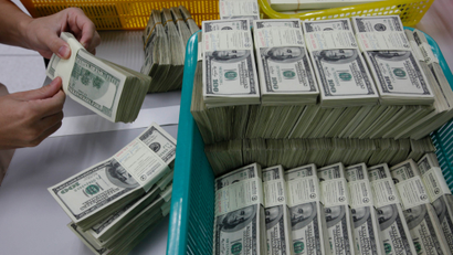 A bank employee counts U.S. hundred dollar bills at Kasikornbank in Bangkok