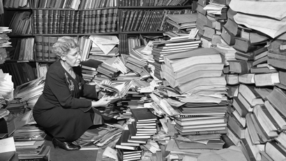 Woman going through huge stack of books
