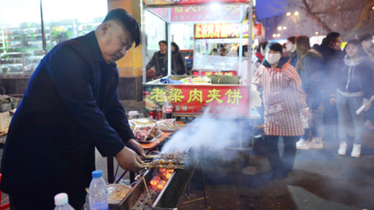 Xia, a 38-year-old lookalike of North Korean leader Kim Jong Un, cooks barbequed lamb at his food stall in Shenyang, Liaoning province March 22, 2014. Street vendor Xia and his food stall in the northern city Shenyang went viral after pictures of him started to circulate on the Internet and in the media last week, local media reported. Picture taken March 22, 2014.