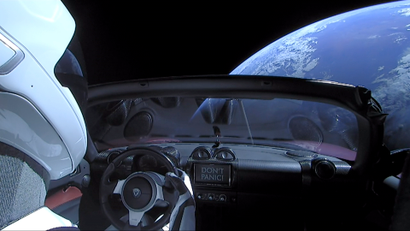 A Tesla roadster hangs in space above the earth after being launched by a SpaceX Falcon Heavy rocket.