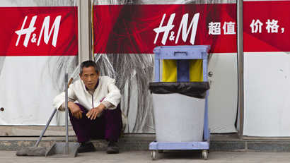 A cleaner sits in front of an H&M store in Guangzhou, China