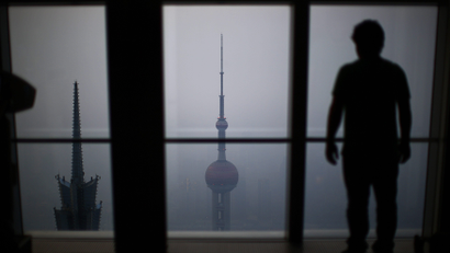 A man looks at the Oriental Pearl TV Tower on a hazy day at Pudong financial district in Shanghai March 18, 2014. China pledged on Sunday that it will make sure that 60 percent of its cities meet national pollution standards by 2020, with pressure growing to make cities liveable as hundreds of millions of migrants are expected to relocate from the countryside.