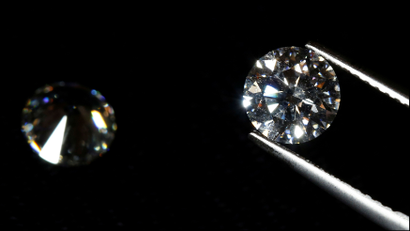 A close up of a diamond in gem-holding tools.