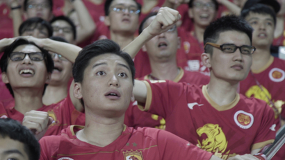 Fans of Guangzhou Evergrande Taobao Football Club cheer on their team at a football match.