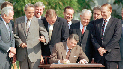 Lawmakers watch closely as Pres. Ronald Reagan signs into law a landmark tax overhaul on the White House South Lawn, Oct. 22, 1986, Washington, D.C. From left, are: Senate Majority Leader Robert Dole of Kansas, Rep. Raymond McGrath, R-N.Y.; Rep. Dan Rostenkowski, D-Ill., Rep. Frank Guerini, D-N.J.; Sen. Russell Long, D-La.; Rep. William Coyne, D-Pa., and Rep. John Duncan, R-Tenn.