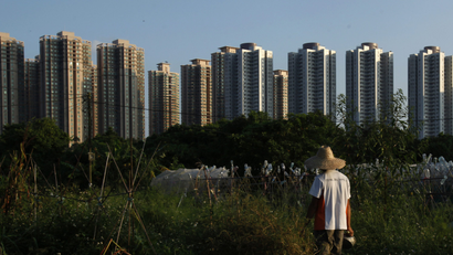 Chan Gar-sun, 26, stands at his farm in front of high-rise residential buildings at Hong Kong New Territories September 25, 2013. Only 18 square kilometres of land in the financial hub are actively farmed, which accounted for 2 per cent of local consumption, according to government figures. Picture taken September 25, 2013. REUTERS/Bobby Yip (CHINA - Tags: SOCIETY CITYSCAPE AGRICULTURE) - RTX16SQ4