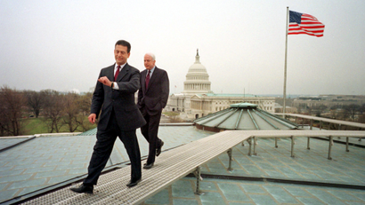 In this March 29, 2001 photo, U.S. Sen. Russ Feingold, D-Wis, checks his watch as he and Sen. John McCain, R-Ariz., walk off the roof of the Russell office building on Capitol Hill after an early morning Time Magazine photo session Thursday morning March 29, 2001 in Washington.