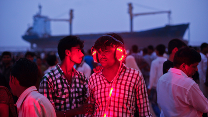 Man wears a headset while listening to a fortune telling machine as people flock to Juhu Beach at low tide to see a cargo ship which ran aground due to rough weather in Mumbai