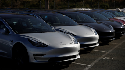A row of new Tesla Model 3 electric vehicles is seen at a parking lot
