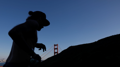 A person running in front of the Golden Gate Bridge in San Francisco; a shadow covers their face.