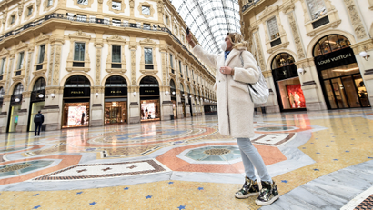A woman wearing a protective face mask takes a selfie in Galleria Vittorio Emanuele II shopping mall