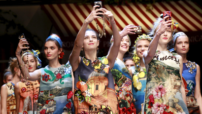 Models take selfies during the parade at the end of the Dolce & Gabbana Spring/Summer 2016 collection during Milan Fashion Week in Italy, September 27, 2015.