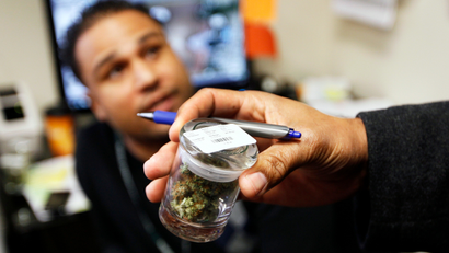 Mark Brown (R), a supervisor with the metro Denver Criminal Enforcement Section of the state of Colorado's Medical Marijuana Enforcement Division looks at the label on a jar of buds as the manager sits in the background at a medical marijuana center in Denver April 2, 2012. Among the states with medical marijuana, Colorado stands out because it has chosen to develop a comprehensive system to regulate marijuana, unlike states that have taken a hands-off approach or left it to local authorities. Voters in Colorado will be asked to decide on legalization in November, in polls that come even as the federal government has clamped down on medical cannabis in several mostly Western states.