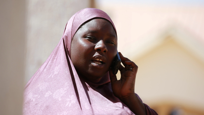 A picture of a woman dressed in a purple hijab making a call