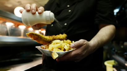 Salt is added to a customer's fish and chips at a restaurant in London.