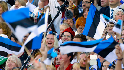 Singers wave Estonia's flags as they perform during the Song and Dance Celebration in Tallinn