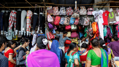 People shop for bags and clothes at roadside shops in a market in Mumbai
