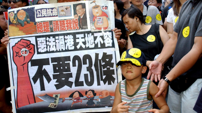A young protester joins protesters with a banner which reads.,"Evil law spells disaster for Hong Kong" and "No article 23" as they prepare to march from a downtown park to Hong Kong's government offices Tuesday, July 1, 2003, to protest a planned anti-subversion law known also as Article 23, that has stirred one of the biggest controversies since Britain returned Hong Kong to China six years ago. Tens of thousands of people turned out to protest on the anniversary of Hong Kong's handover. (AP Photo/Anat Givon)