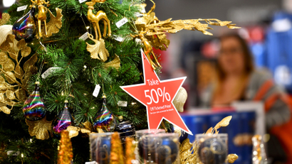 A star shaped placard hanging from a Christmas tree states "Take 50% Off Ticketed Price"