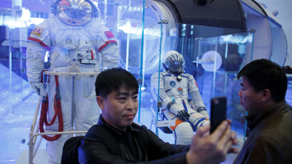 A visitor takes a selfie in front of a Chinese space suit at an exhibition marking the 40th anniversary of China's reform and opening up at the National Museum of China in Beijing, China November 14, 2018. REUTERS/Thomas Peter