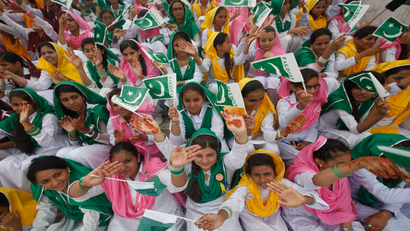 Female students wave Pakistan's national flag at a ceremony to celebrate the country's Independence Day at the mausoleum of Muhammad Ali Jinnah in Karachi