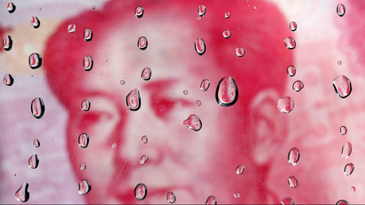 A portrait of former Chinese leader Mao Zedong on a yuan banknote is reflected in water droplets in this picture illustration taken in Taipei October 8, 2010. REUTERS/Nicky Loh