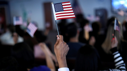 New American citizens wave American flags after taking the Oath of Allegiance during a naturalization ceremony in Newark