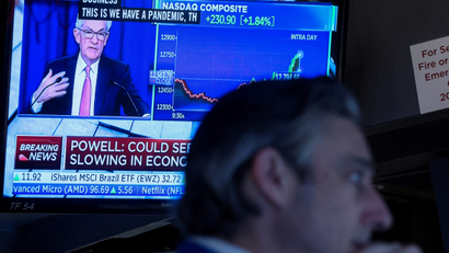 A trader works, as Federal Reserve Chair Jerome Powell is seen delivering remarks on a screen, on the floor of the New York Stock Exchange (NYSE).