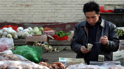 Fruit and vegetables can be seen behind a man selling pork as he checks his money at a small roadside market in central Beijing March 1, 2011. China's annual consumer price index (CPI) may reach 4.5 percent in the first quarter and peak this year in the second quarter, the official Shanghai Securities News on Monday quoted a research report as saying. In one sign of the accumulating pressures, core inflation, stripped of volatile food prices, jumped to 2.6 percent year on year, the highest in at least a decade, from 2.1 percent a month earlier. REUTERS/David Gray