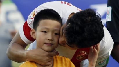 China's captain Zheng Zhi kisses a mascot as the team line up before the start of their Asian Cup Group B soccer match against North Korea at the Canberra stadium in Canberra January 18, 2015.