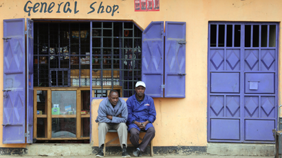 Two men sit in front of a retail shop near Naivasha town in Kenya.