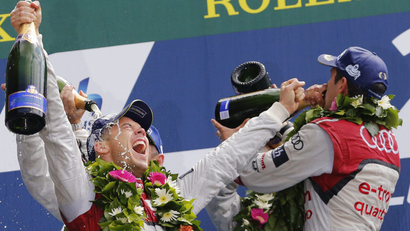 Audi R18 E-Tron Quattro Number 2 drivers Andre Lotterer of Germany and Marcel Fassler of Switzerland celebrate with champagnes on podium after winning the Le Mans 24-hour sportscar race in Le Mans, central France June 15, 2014.
