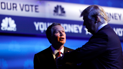 Republican U.S. presidential candidate and Ohio Governor John Kasich (L) talks with businessman Donald Trump (R) as Trump looks at his watch at the conclusion of the 2016 U.S. Republican presidential candidates debate held by CNBC in Boulder, Colorado, October 28, 2015.