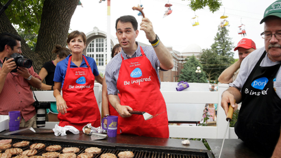 Republican presidential candidate Wisconsin Gov. Scott Walker holds up a pork chop bone while working the grill at the Iowa Pork Producers tent during a visit to the Iowa State Fair, Monday, Aug. 17, 2015, in Des Moines, Iowa.