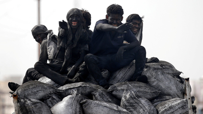 An image of coal workers travel on the back of their lorry in Barsana