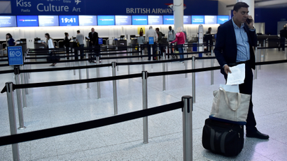 A man waits with his luggage at Gatwick Airport in southern England