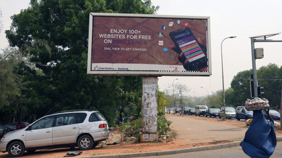 A woman walks past an advertising billboard for Free Basics, a service from Facebook, along a street in Abuja, Nigeria April 4, 2018.