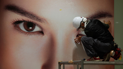 A worker installs an advertising billboard for a cosmetics company in Tokyo, Sunday, Dec. 30, 2012. (AP Photo/Shizuo Kambayashi)