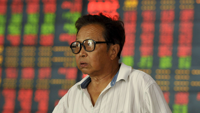 An investor stands in front of an electronic board showing stock information at a brokerage house in Fuyang, Anhui province, China, July 30, 2015. China stocks fell on Thursday after state media reported that banks were investigating their exposure to the stock market through wealth management products and loans collateralised with stocks. REUTERS/China Daily