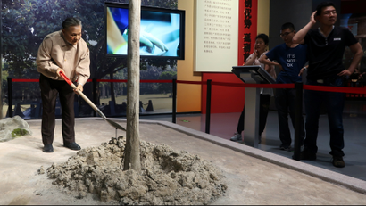 Visitors look at an exhibit showing the former Chinese leader Deng Xiaoping planting a tree.