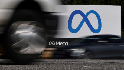 cars drive past the meta logo