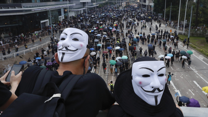 Anti-government protesters wearing masks march past police headquarters in Hong Kong, Tuesday, Oct. 1, 2019. Thousands of black-clad pro-democracy protesters defied a police ban and marched in central Hong Kong on Tuesday, urging China's Communist Party to "return power to the people" as the party celebrated its 70th year of rule.